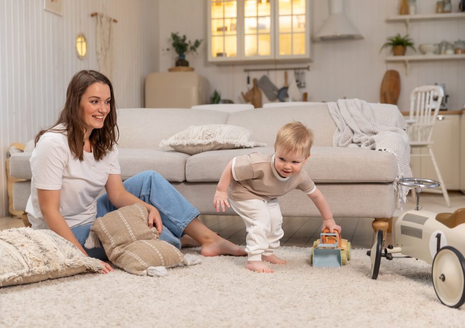 Happy family at home. Mother and baby boy playing with toys at home indoors. Little toddler child and babysitter nanny having fun together. Young woman mum kid son rest in living room
